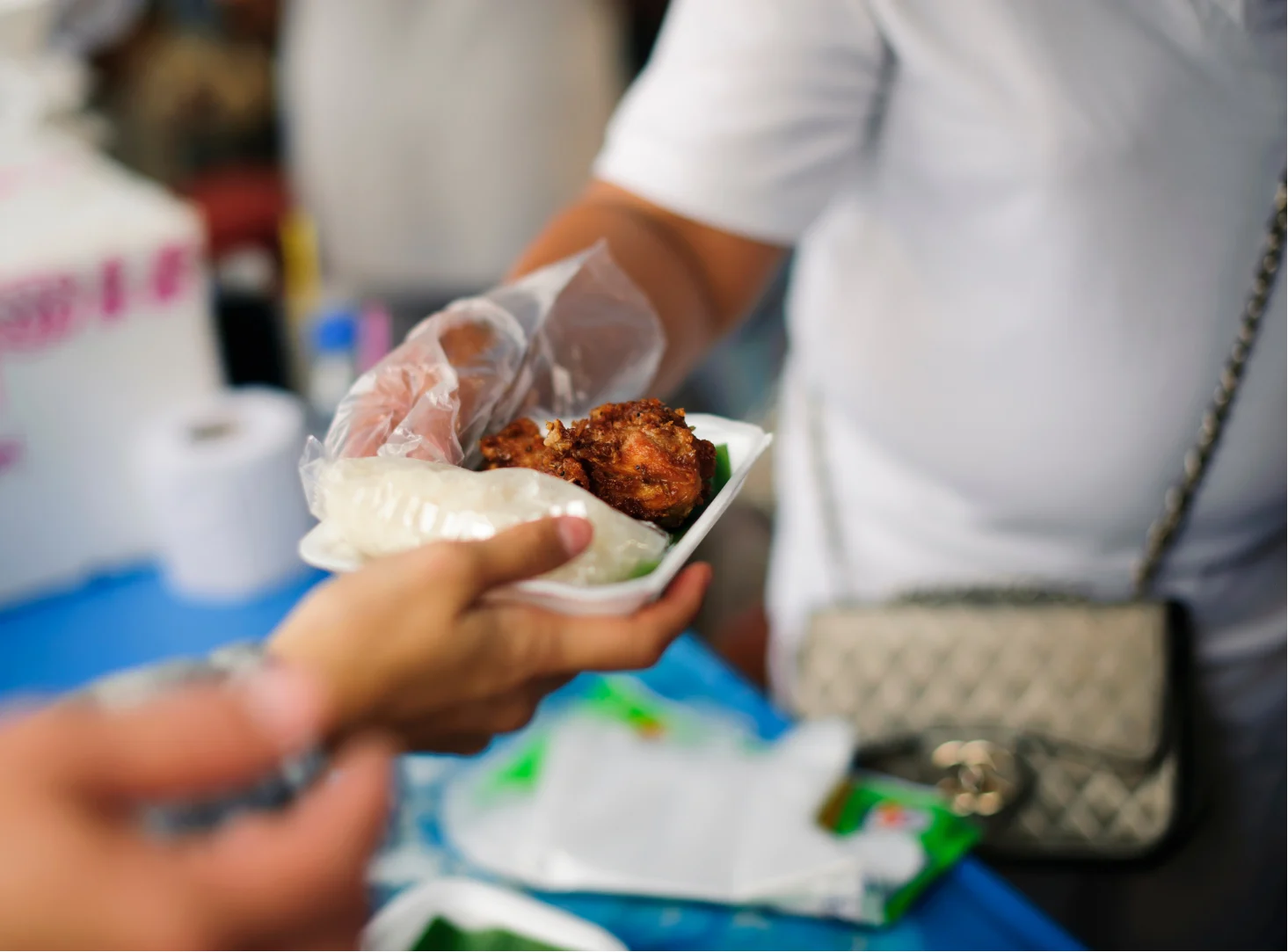 A volunteer hands a plate of food to a neighbor during an Ihsan Initiative distribution